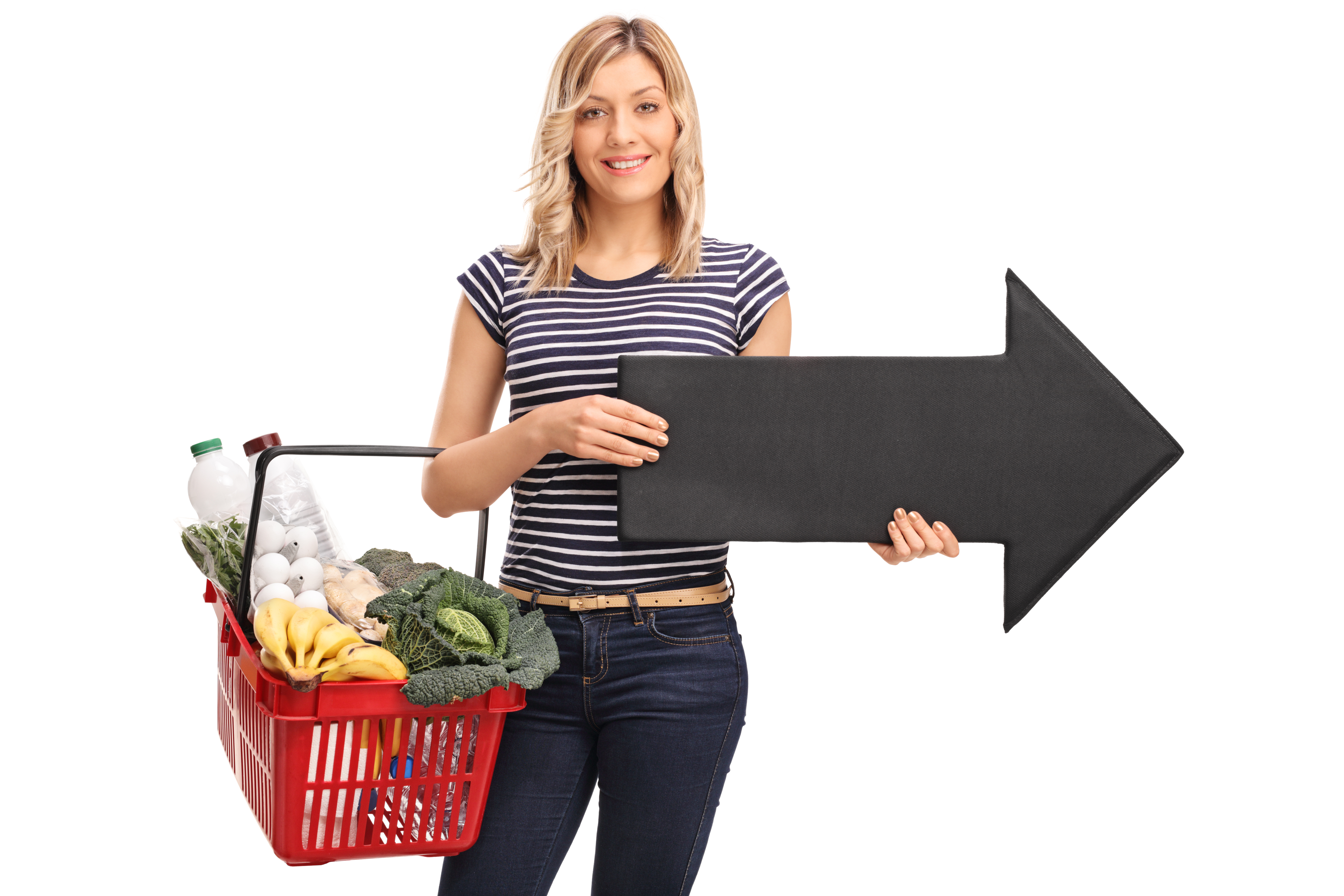 Young woman holding a shopping basket and a big black arrow pointing right isolated on white background